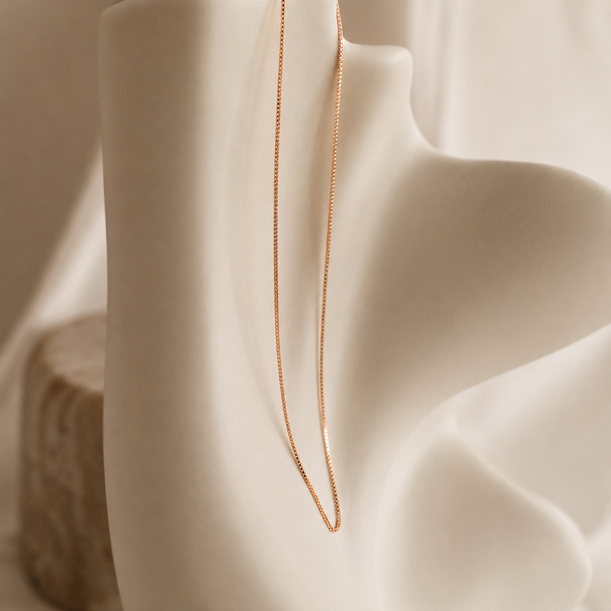 Delicate gold chain necklace on a soft beige fabric background